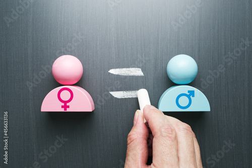 Concept image of gender equality. Female and male symbols. Hand writing equal sign on blackboard.