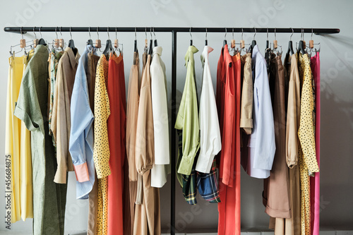 Image of fashion dresses and shirts hanging on the rack in the clothing store