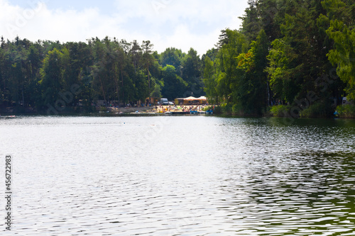 Jezioro Srebrne w Osowcu latem. Widok na jezioro, las i plażę z turystami