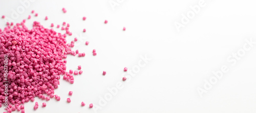 Pink granules of polypropylene or polyamide on a white background. Plastics and polymers industry. Copy space. Banner