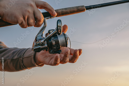 Fishing rod with a spinning reel in the hands of a fisherman. Fishing background