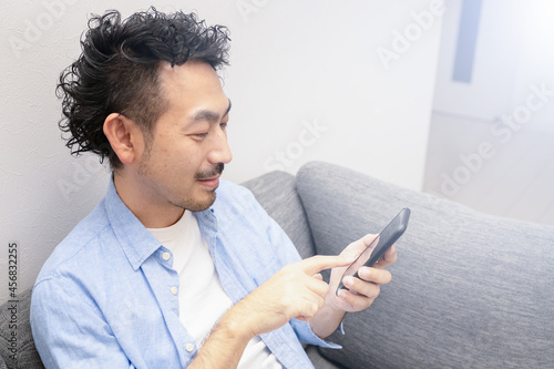 ECサイトの決済やSNSコミニケーションに使いやすいタップして何か決済している日本人の中年男性 2横向き