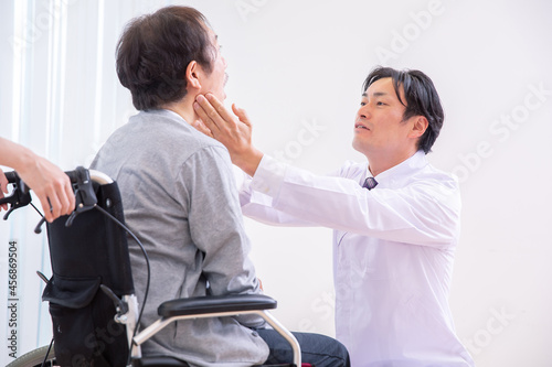 口を見る医師と車椅子に乗った患者（歯医者） 