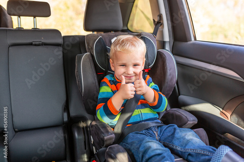 Little baby boy sitting on a car seat buckled up in the car.