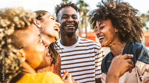 Young happy people laughing together - Multiracial friends group having fun on city street - Diverse culture students portrait celebrating outside - Friendship, community, youth, university concept.