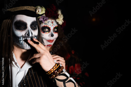 Man and woman in paired halloween costumes. Body art santa muerte and skeleton