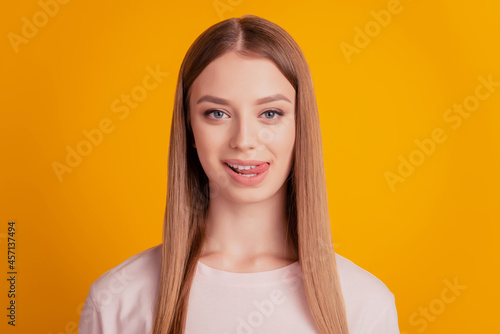 Portrait of flirty playful cute lady look camera stick out tongue on yellow background