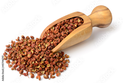dried Szechuan peppercorns in the wooden scoop, isolated on the white background