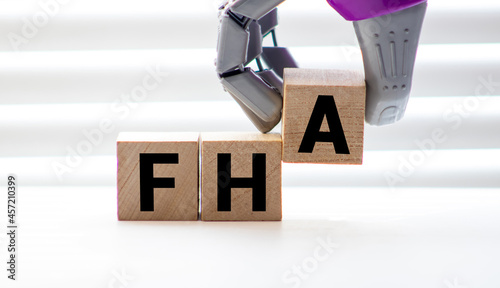 FHA symbol. Wooden cubes form the word 'FHA, federal housing administration'. Beautiful grey background, copy space.