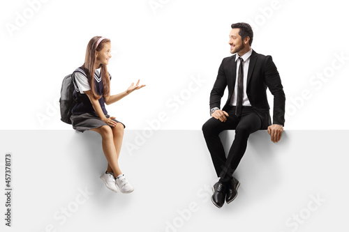 Schoolgirl and a businessman sitting on a blank panel and talking