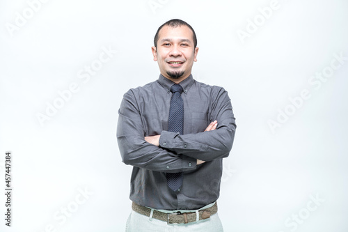 An Asian working man in an office suit is standing with her arms crossed and confidently smiling faces, on white background.