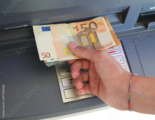 hand picking up banknotes from an ATM cash machine in Europe