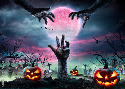 Zombie Hands Rising Out Of A Graveyard With Full Moon And Halloween Pumpkins