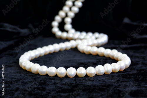 Natural pale pearl necklace on a black velvet background, closeup