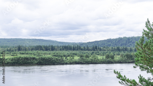 Panorama of a forest river and mountains overgrown with coniferous forests. Summer landscape coniferous forest and river