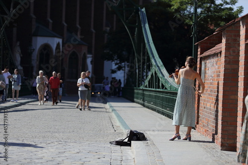 Skrzypaczka gra na skrzypcach na moście, piękna młoda dziewczyna, Wrocław.