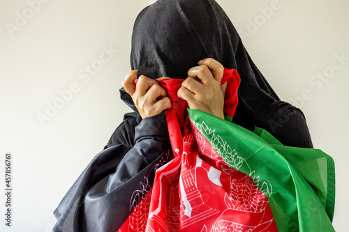 Desperate Woman in Traditional Afghan Dress Pressing Desperate Country Flag to Her Face, Concept, Afghan Women's Drama