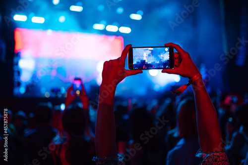 Hand with a smartphone records live music festival, Taking photo of concert stage, live concert. Youth, party, vacation concept.