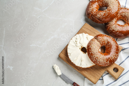 Delicious bagel with cream cheese on light table, flat lay. Space for text