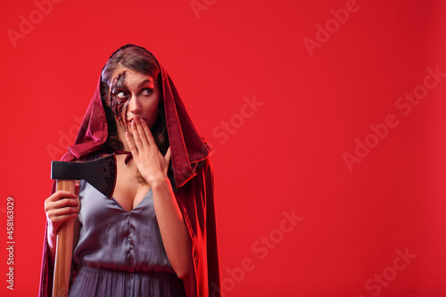 Surprised woman with Halloween makeup and axe on color background