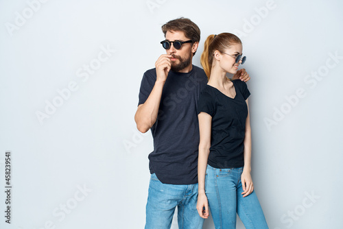 a young couple in black t-shirt sunglasses posing light background