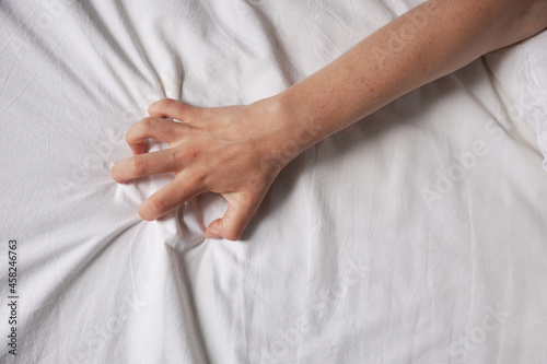 female hand grabs bed sheet