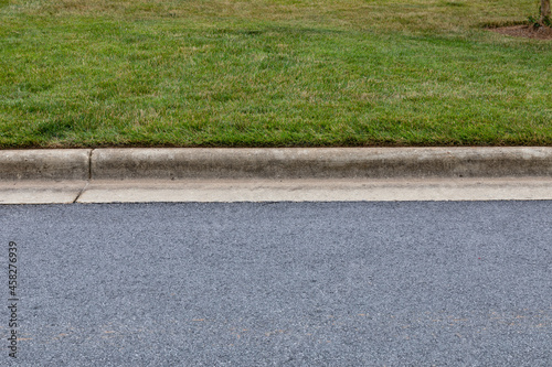 Carefully edged grass alongside extruded concrete curbing and asphalt street, creative copy space options, horizontal aspect