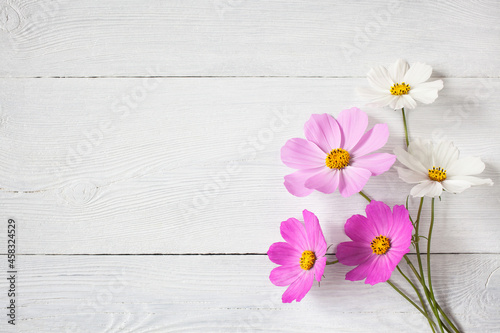 Bouquet of pink and white cosmos flowers on a wooden background. Postcard for congratulations, space for text.