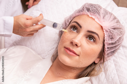 closeup of woman applying ozone to her face for cosmetic treatment.