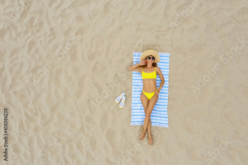 Woman sunbathing on beach towel at sandy coast, aerial view. Space for text