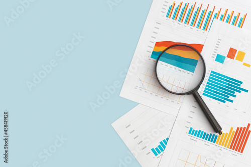 Business graphs, charts and magnifying glass on table. Financial development, Banking Account, Statistics