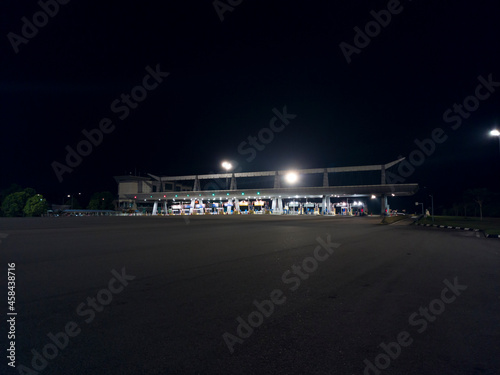 A wide view of the toll plaza at night with floodlights. Selective focus points