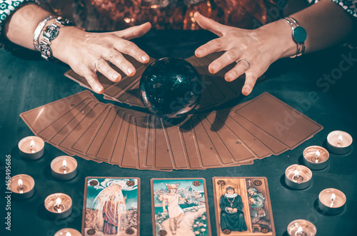 Tarot reader with tarot cards.Tarot cards face down on table near burning candles and crystal ball.