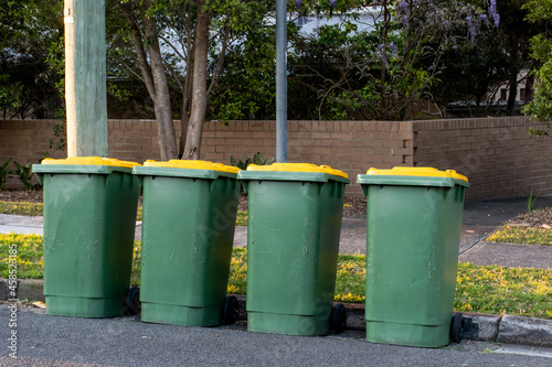 Australian garbage wheelie bins with colourful lids for recycling household waste on the street kerbside for council rubbish collection.