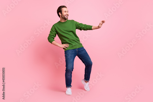 Full size portrait of positive satisfied person hand on waist look empty space isolated on pink color background