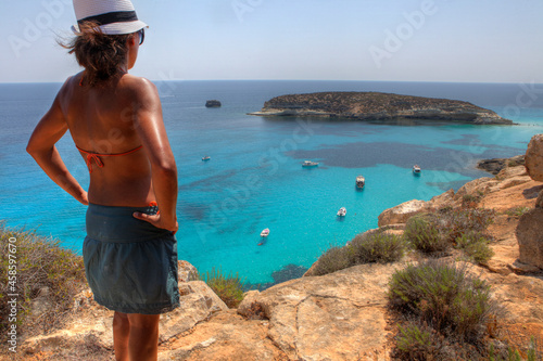 Girl in front of the Island of Rabbits in Lampedusa, Sicily, Italy