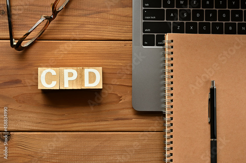 On the table there is a word cube lined CPD with laptop computers and glasses. It is an abbreviation for the word Continuing Professional Development.