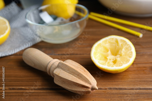 Citrus reamer and fresh lemons on wooden table