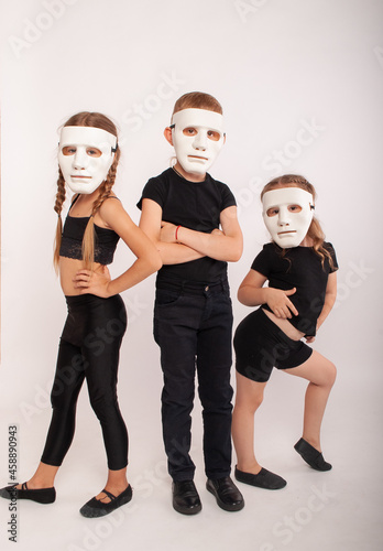 young children depict acting in white masks of mimes on a white stage in isolation with a place for tects for the day of the theater