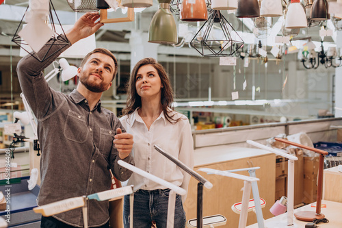 Young couple choosing chandelier in building center