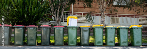 Australian garbage wheelie bins with colourful lids for general and recycling household waste on a street kerbside for council rubbish collection.