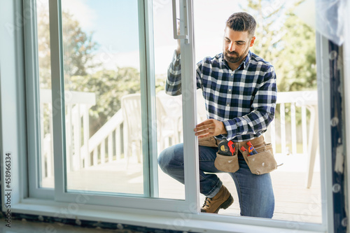 handsome young man installing bay window in a new house construction site