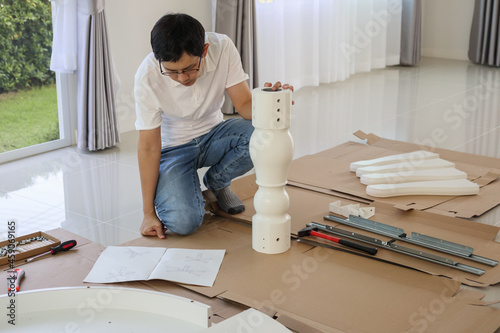 Man assembling white table furniture at home