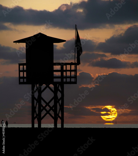 Dawn in the distance and in the foreground you can see the silhouette of a lifeguard tower on a deserted beach