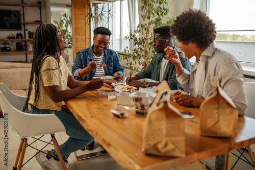 Group of young adults eating take out food at home