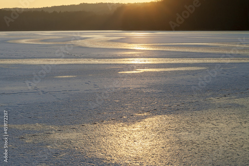 skuta lodem tafla jeziora w zachodzącym zimowym słońcu