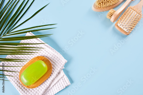 Green soap bar on soap wooden dish and bath towel, light blue background