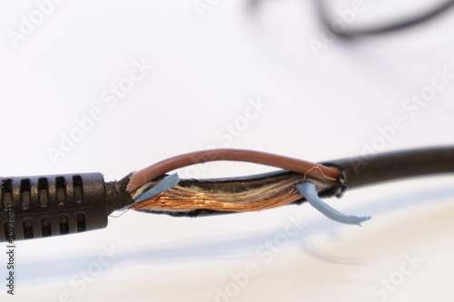 Broken power cord for home electrical appliances, electric tools. Damaged cable insulation. Close-up, soft focus