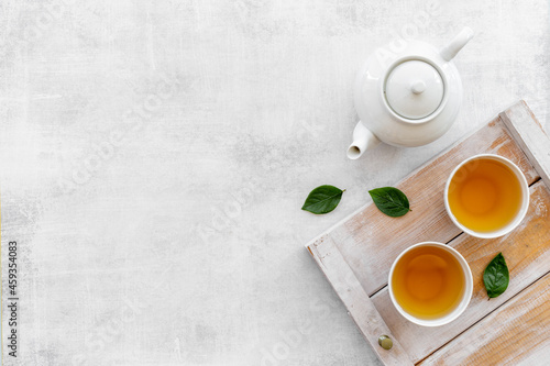 Ceramic white teapot and black tea in two cups, top view