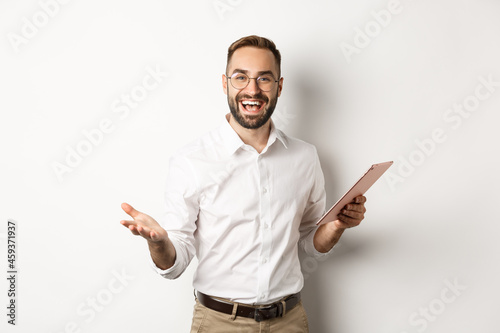 Satisfied businessman praising good work, reading report on digital tablet, standing happy against white background